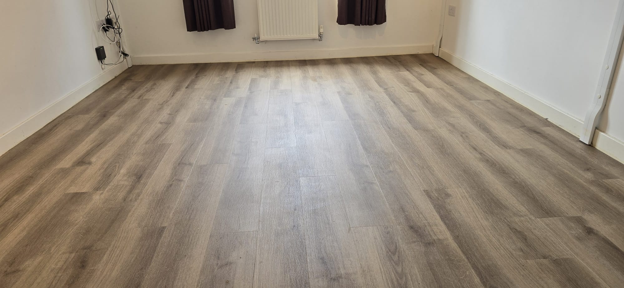 Wide grey-brown plank flooring fitted wall to wall in a living room in Northampton