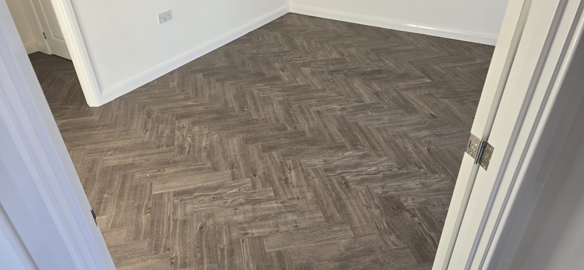 Dark oak herringbone LVT flooring fitted in a bedroom in Northampton